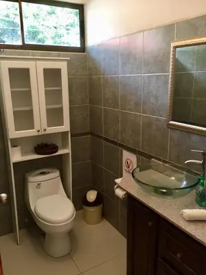 a bathroom with a toilet and a sink and a mirror at Casa Playa Bahia Ballena de Osa in Uvita