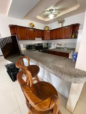 a kitchen with a granite counter top and wooden cabinets at Casa Playa Bahia Ballena de Osa in Uvita