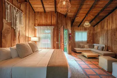 a bedroom with a large bed and a living room at Hotel & Spa Escondite de la Montaña in Sabana Redonda