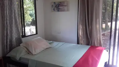 a bed sitting in a bedroom with a window at Villa De Los Monos, casitas equipadas en Guanacaste in Matapalo