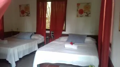 a bedroom with two beds with red curtains and a window at Villa De Los Monos, casitas equipadas en Guanacaste in Matapalo