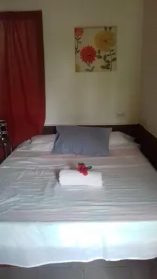 a bed with a white towel and a red flower on it at Villa De Los Monos, casitas equipadas en Guanacaste in Matapalo