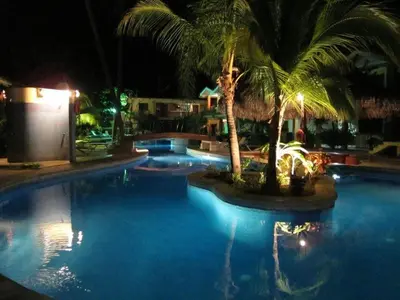 a swimming pool with palm trees in a resort at night at Cocomarindo Condo #72 in Coco