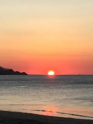 a sunset on the beach with the sun setting at Cocomarindo Condo #72 in Coco