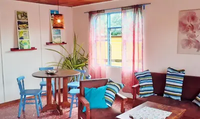 a living room with a couch and a table and chairs at Montaña Linda Guest House Orosi in Orosí