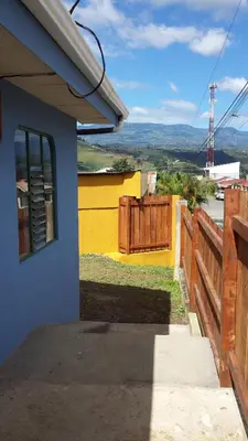 a house with a wooden fence and a yard at Montaña Linda Guest House Orosi in Orosí
