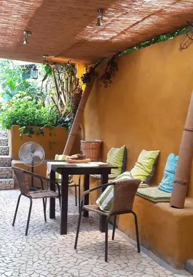 a patio with a table and chairs and a bench at Montaña Linda Hostel Orosi in Orosí