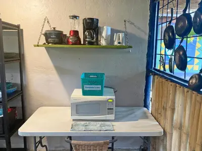 a microwave sitting on a table in a kitchen at Montaña Linda Hostel Orosi in Orosí