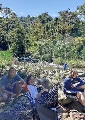 three people sitting in lawn chairs on the beach at Montaña Linda Hostel Orosi in Orosí