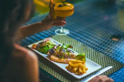 a person sitting at a table with a plate of food and a drink at Jungle Vista Boutique Hotel in Manuel Antonio