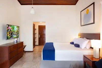 a bedroom with a bed and a dresser and a television at The Coast Beachfront Hotel in Tamarindo