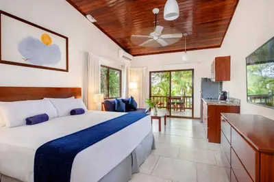 a bedroom with a large bed and a kitchen at The Coast Beachfront Hotel in Tamarindo