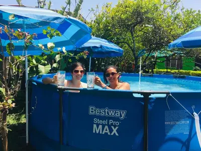 two people are sitting in a swimming pool at Hotel Your House in Alajuela City