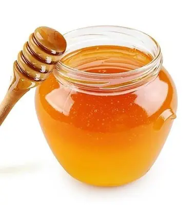 a glass jar of honey with a wooden spoon at Hotel Your House in Alajuela City