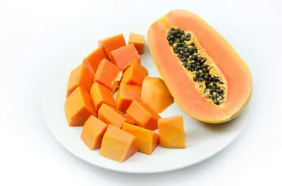 a plate with a papaya and a melon and cut vegetables at Hotel Your House in Alajuela City