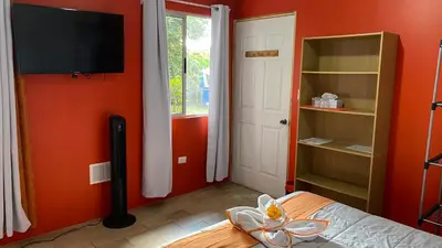 a bedroom with orange walls and a bed with a flat screen tv at Hotel Your House in Alajuela City