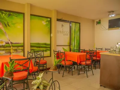 a dining room with orange tables and chairs at Hotel Bamboo Aeropuerto in Alajuela City