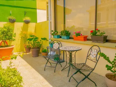 a patio with two chairs and a table and potted plants at Hotel Bamboo Aeropuerto in Alajuela City