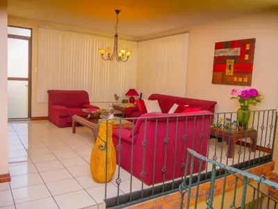 a living room with a red couch and a guitar at Hotel Bamboo Aeropuerto in Alajuela City