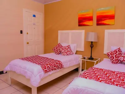 two beds in a room with yellow walls at Hotel Bamboo Aeropuerto in Alajuela City