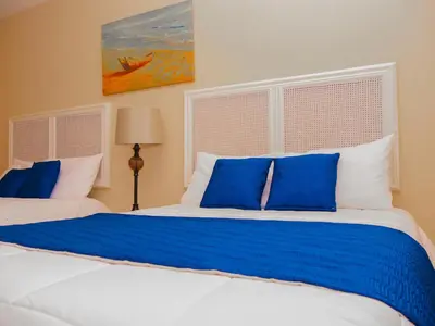 a bedroom with two beds with blue and white pillows at Hotel Bamboo Aeropuerto in Alajuela City