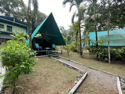 a tent in front of a house with palm trees at Corcovado Adventures in Drake