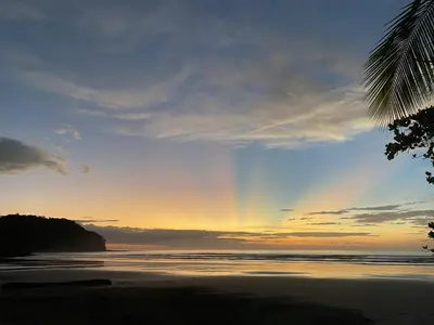 a rainbow in the sky over a beach at Alouatta Playa Coyote in San Francisco