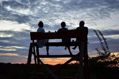 three people sitting on a bench watching the sunset at Alouatta Playa Coyote in San Francisco
