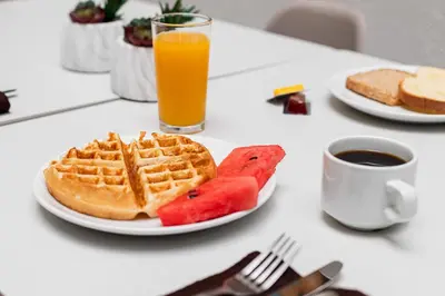 a plate of waffles and fruit and a glass of orange juice at Apartotel Tairona in San Pedro