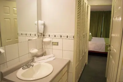 a bathroom with a sink and a mirror and a bed at Apartotel Tairona in San Pedro
