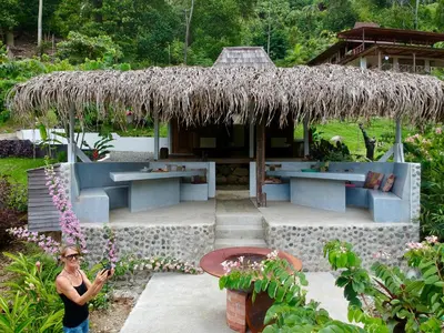 a woman standing in front of a building with a straw roof at Uvita Bali Bosque Retreat in Uvita