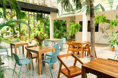 a restaurant with tables and chairs and plants at Wide Mouth Frog Quepos in Manuel Antonio