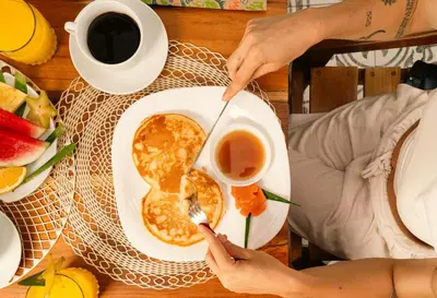 a person eating a plate of pancakes with a cup of coffee at Wide Mouth Frog Quepos in Manuel Antonio