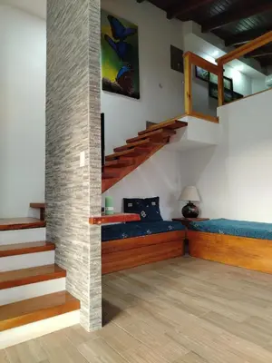 a living room with stairs and a blue couch at Los Héroes in Nuevo Arenal
