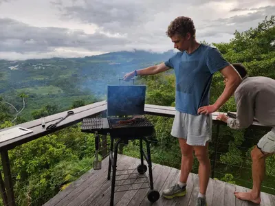 a man cooking food on a grill on a deck at Volare in Turrialba