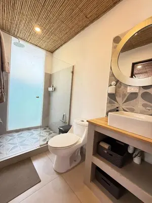 a bathroom with a toilet and a glass shower at Nirvana Beach Home in Paraíso