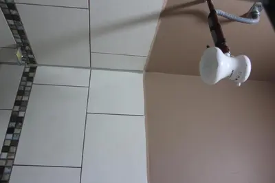 a bathroom with a white tiled floor and a light at Hotel Pecos Bill in San José