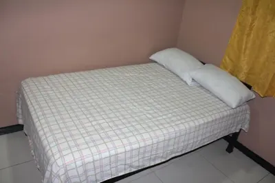 a bed with a white pillow on top of it at Hotel Pecos Bill in San José