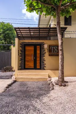 a house with a wooden door and a tree at Tamarindo Sunshine in Tamarindo