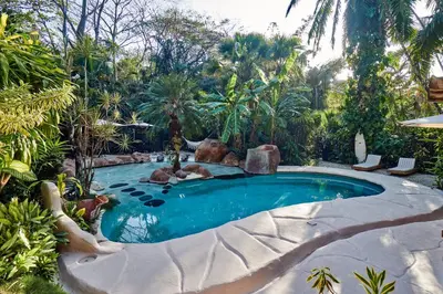 a swimming pool in a garden with a resort at Havana Lodge in Mal País
