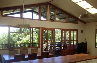a dining room with a large table and windows at Casa Cañitas in Monteverde Costa Rica