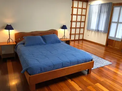 a bedroom with a bed with blue sheets and two lamps at Casa Cañitas in Monteverde Costa Rica