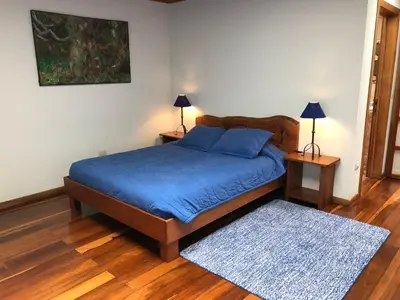 a bedroom with a bed with blue sheets and a rug at Casa Cañitas in Monteverde Costa Rica