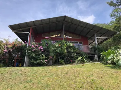 a red house with a balcony and flowers at Casa Cañitas in Monteverde Costa Rica