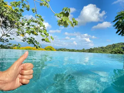 a hand pointing to the water in a lake at Casa Libertinn in Manuel Antonio