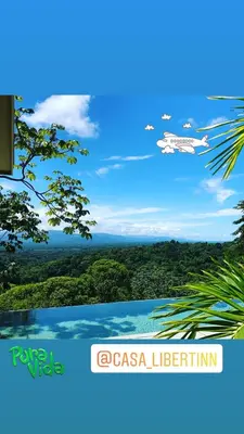 an airplane in the sky over a forested at Casa Libertinn in Manuel Antonio