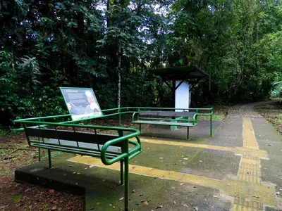 two benches sitting in a park with a sign at La Selva Biological Station in Sarapiquí
