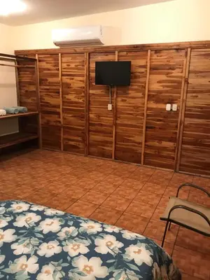 a bedroom with a bed and a flat screen tv at Hotel Cabañas La Teca in Liberia