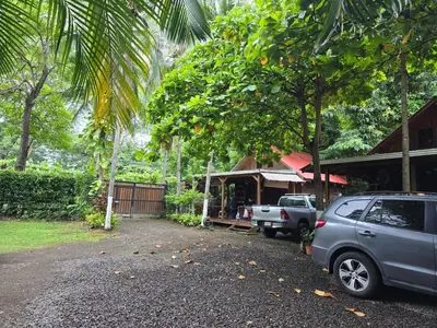 a car parked in front of a building with trees at Congos Hostal y Camping in Playa Hermosa