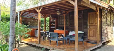 a wooden cabin with a table and chairs on a deck at Congos Hostal y Camping in Playa Hermosa